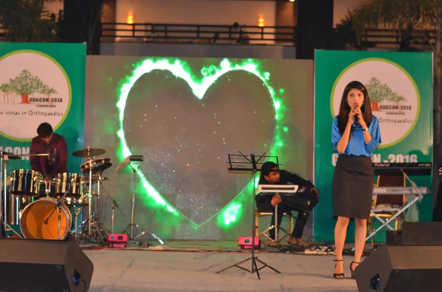 Man and woman speaking on stage at night with blue lighting