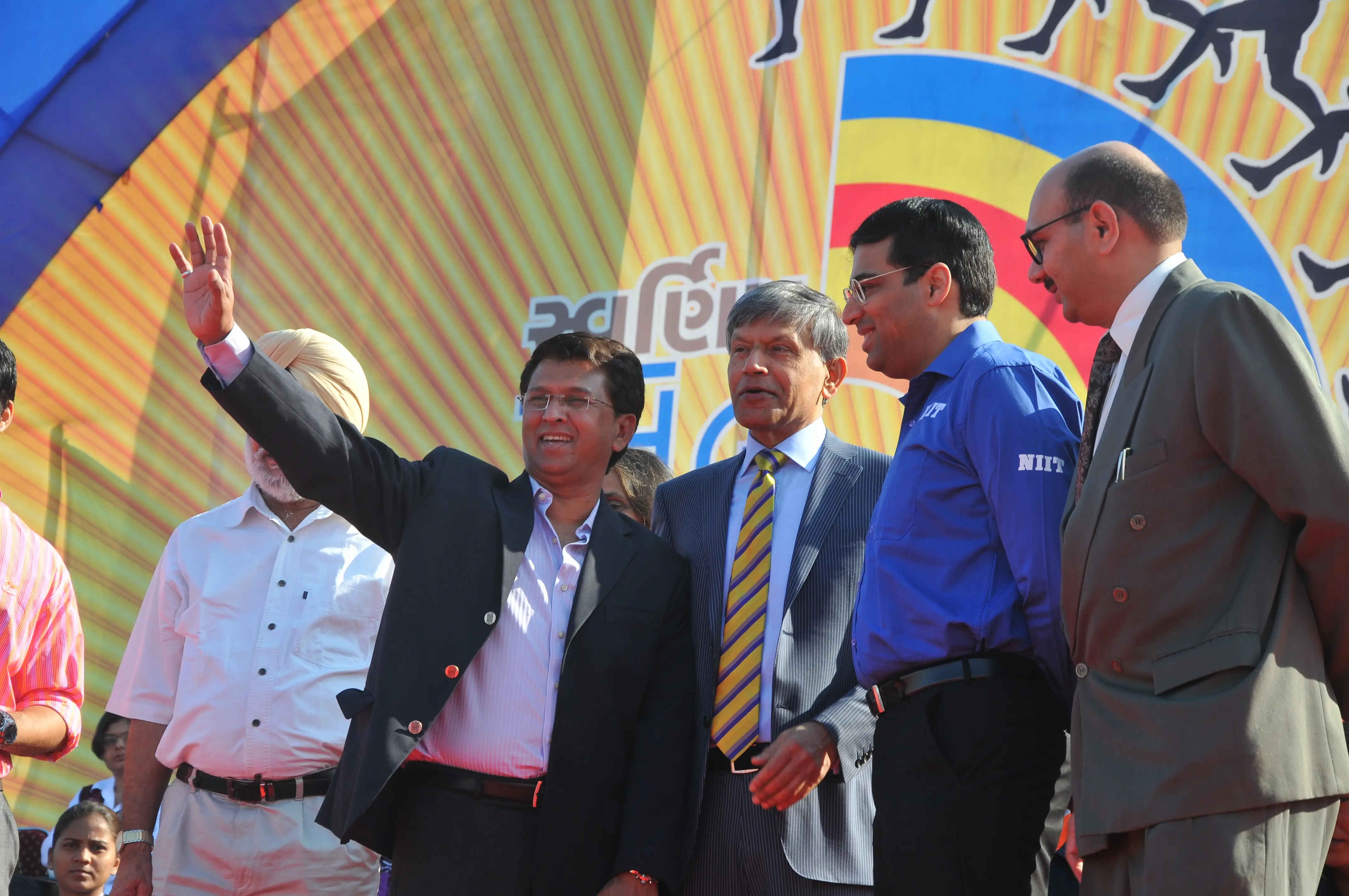 Men lighting ceremonial lamp at event with ITT banner in background
