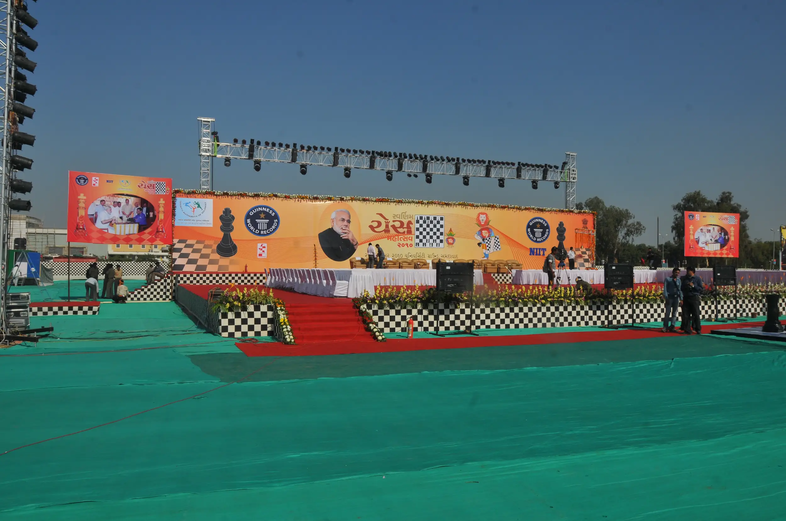 Balloon arch in orange, black, and white colors framing an ITT logo board lit with warm lights
